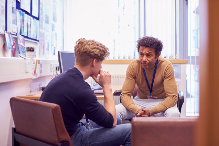 high school counselor talking with teen boy